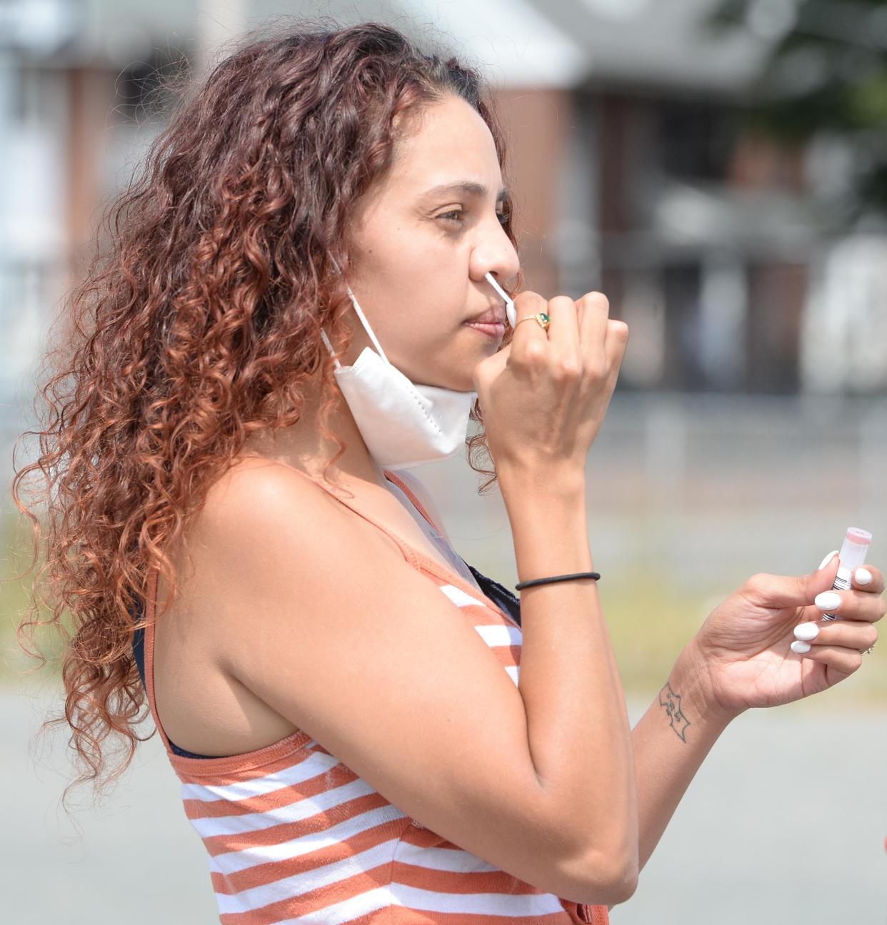 Yaritza Higgns, 27, takes a COVID-19 self test at the free, walk-up coronavirus testing site at the Crescent Court public housing complex in Brockton, run by Brockton Area Multi-Services Inc. through the state's Stop the Spread program, Thursday, Aug. 13, 2020.