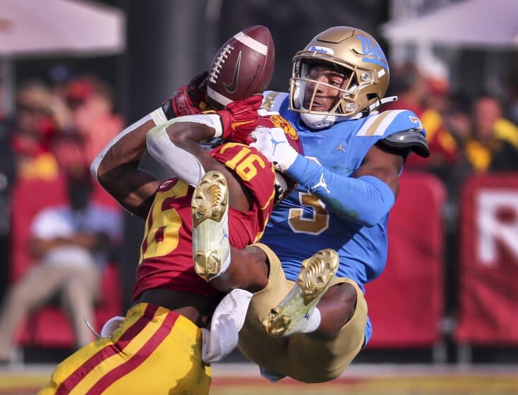 Los Angeles, CA - November 20: UCLA cornerback Cameron Johnson, right, bats a pass away from USC wide receiver Tahj Washington in the second quarter at Los Angeles Memorial Coliseum in Los Angeles on Saturday, Nov. 20, 2021. (Allen J. Schaben / Los Angeles Times)