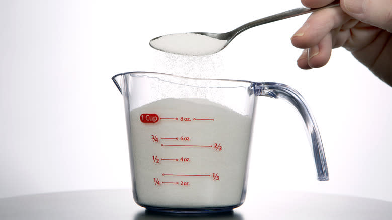 spooning sugar into measuring cup