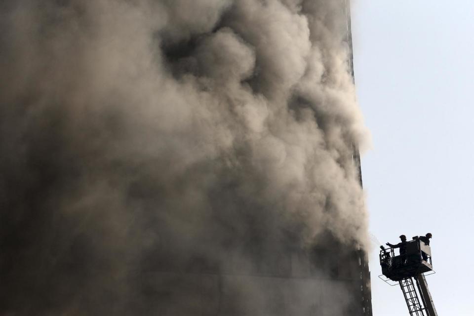 Bomberos iraníes trabajan en la extinción de un incendio en el edificio Plasco, en el centro de Teherán, el 19 de enero de 2017. El rascacielos, envuelto en llamas, colapsó mientras decenas de bomberos intentaban apagar las llamas. (AP Foto/Vahid Salemi)