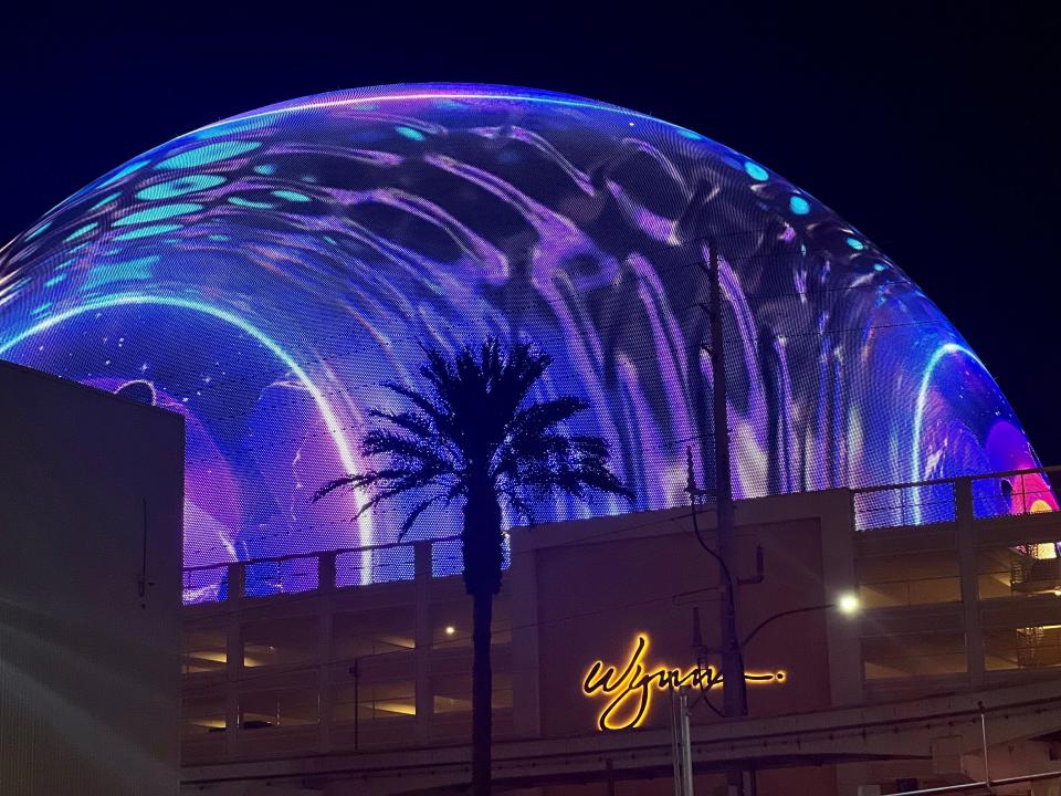 The Sphere illuminated purple and blue over the Wynn hotel.