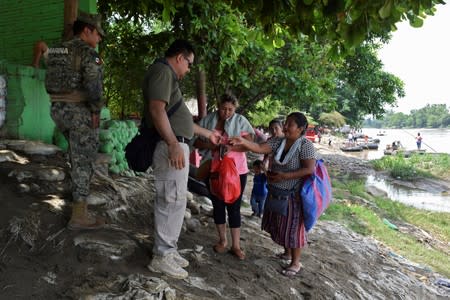 Agent of the National Migration Institute and a member of Mexico's National Guard check the IDs of people who have crossed the Suchiate River on a raft from Tecun Uman, Guatemala, to Ciudad Hidalgo, as seen from Ciudad Hidalgo