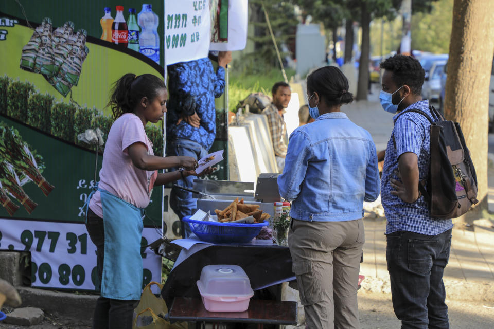 Pedestrians buy food from a street vendor in the Piazza old town area of the capital Addis Ababa, Ethiopia Thursday, Nov. 4, 2021. Urgent new efforts to calm Ethiopia's escalating war are unfolding Thursday as a U.S. special envoy visits and the president of neighboring Kenya calls for an immediate cease-fire while the country marks a year of conflict. (AP Photo)