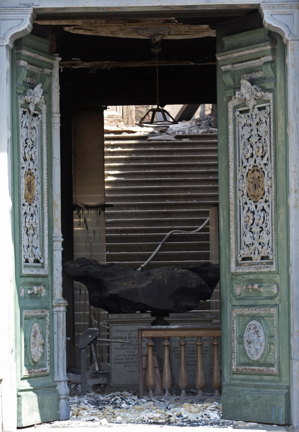 In this Sept. 3, 2018 photo, a meteorite on exhibit at the National Museum is seen through a door after an overnight fire in Rio de Janeiro, Brazil. The esteemed museum houses artifacts from Egypt, Greco-Roman art and some of the first fossils found in Brazil. (AP Photo/Silvia Izquierdo)