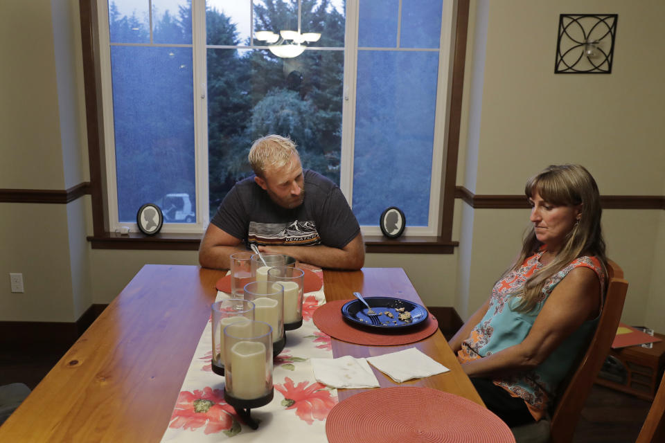 In this Aug. 21, 2019 photo, Stacy Mullen-Deland, right, a former Spanish teacher at Sky Valley Education Center, and husband Eric eat dinner in their home in Snohomish, Wash. Mullen-Deland says she and her children have dealt with numerous ailments since they spent time at the school, including migraines, thyroid problems and learning and neurological issues. She and her husband are part of a lawsuit filed against the school district, the local health department and Monsanto, the maker polychlorinated biphenyls, or PCBs, which several families believe have made them sick. (AP Photo/Ted S. Warren)