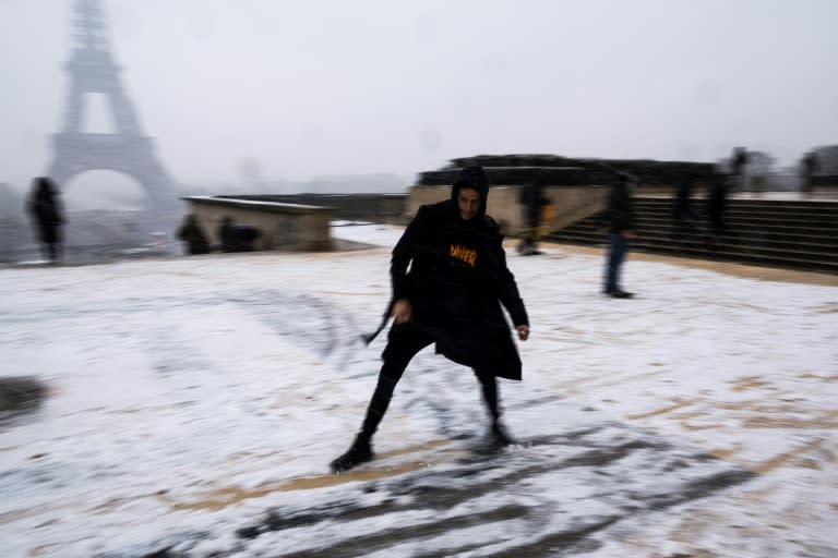 A man slides across snow in front of the Eiffel Tower, which has forced to close after a wintry blast hit France