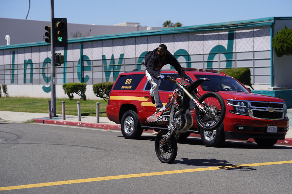 Riders perform motorcycle tricks before the start of the third annual Juneteenth Drive-Thru Parade at Inglewood High School in Inglewood. Calif., Sunday, June 19, 2022. (AP Photo/Damian Dovarganes)