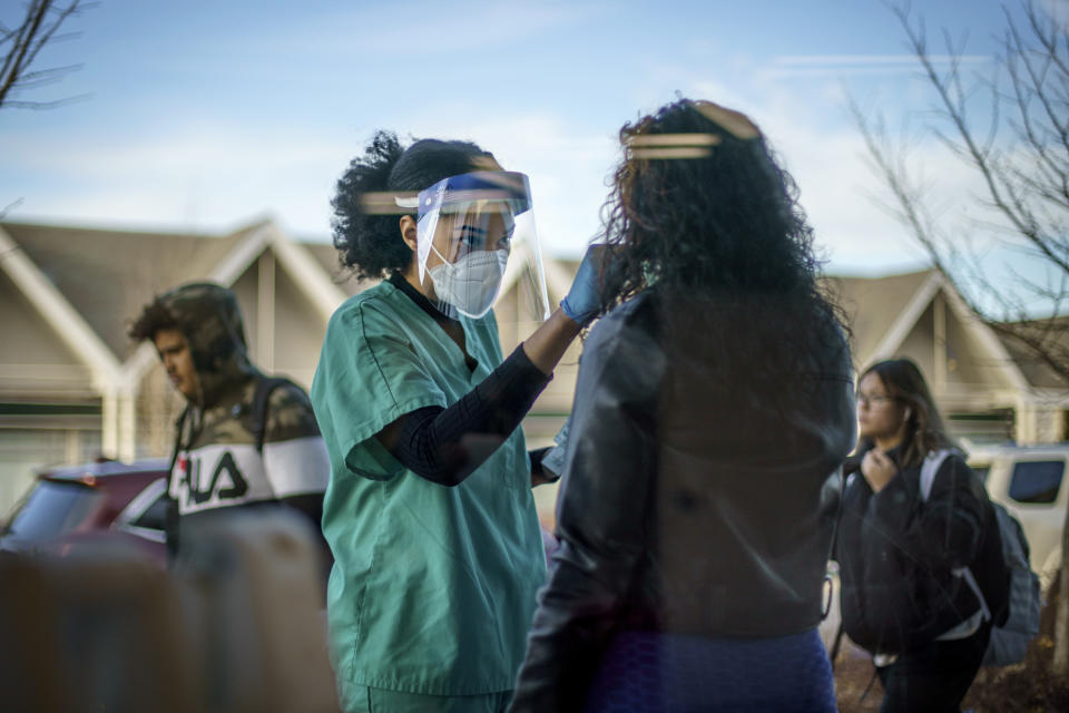 Maya Goode, a COVID-19 technician, performs a test on Jessica Sanchez outside Asthenis Pharmacy in Providence, R.I., Tuesday, Dec. 7, 2021. Even as the U.S. reaches a COVID-19 milestone of roughly 200 million fully-vaccinated people, infections and hospitalizations are spiking, including in highly-vaccinated pockets of the country like New England. (AP Photo/David Goldman)