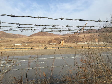 A barbed-wire fence separating North Korea from China is seen in this photo taken from the Chinese border city of Hunchun, China, March 18, 2015. REUTERS/Staff