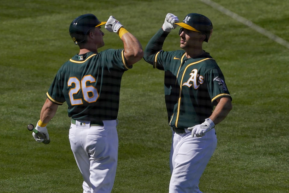 Oakland Athletics' Matt Olson greets Matt Chapman (26) after hitting a solo home run against the Los Angeles Angels during the third inning of a spring training baseball game, Friday, March 5, 2021, in Mesa, Ariz. (AP Photo/Matt York)