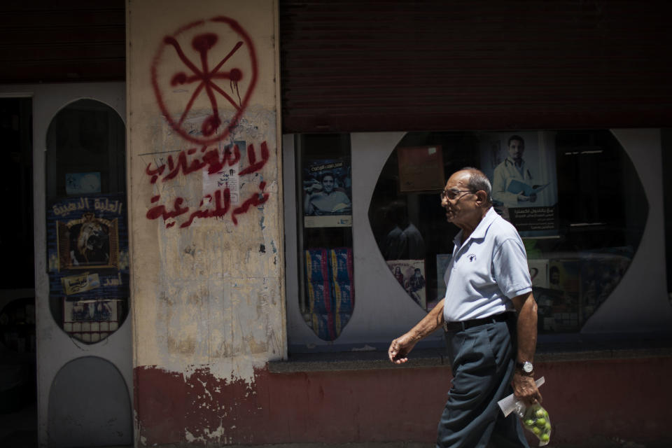 An Egyptian man walks in front of a pharmacy marked with anti-Coptic and anti-coup graffiti in Assiut, Upper Egypt, Tuesday, Aug. 6, 2013. Islamists may be on the defensive in Cairo, but in Egypt's deep south they still have much sway and audacity: over the past week, they have stepped up a hate campaign against the area's Christians. Blaming the broader Coptic community for the July 3 coup that removed Islamist President Mohammed Morsi, Islamists have marked Christian homes, stores and churches with crosses and threatening graffiti. Arabic grafitti reads, "No to the coup and yes to legitimacy." (AP Photo/Manu Brabo)