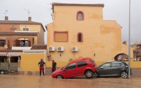 A firefighter checks damaged cars after heavy rains in Los Alcazeres