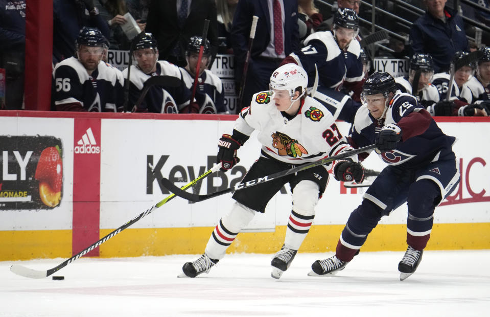 Chicago Blackhawks left wing Lukas Reichel, left, collects the puck as Colorado Avalanche center Nathan MacKinnon defends in the second period of an NHL hockey game Monday, March 20, 2023, in Denver. (AP Photo/David Zalubowski)