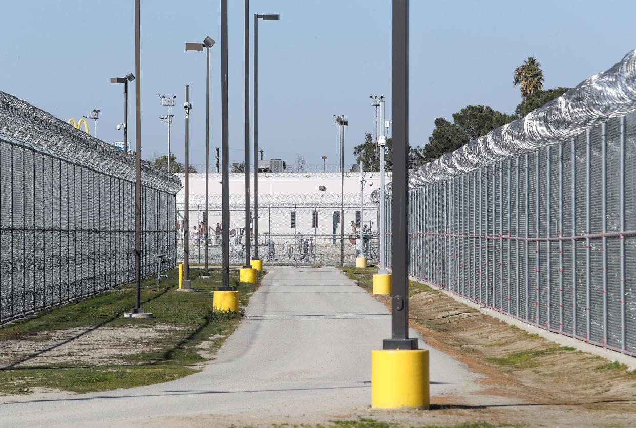 Inmates can be seen from a public street outside the Golden State Modified Community Correctional Facility in McFarland, California, February 12, 2020.