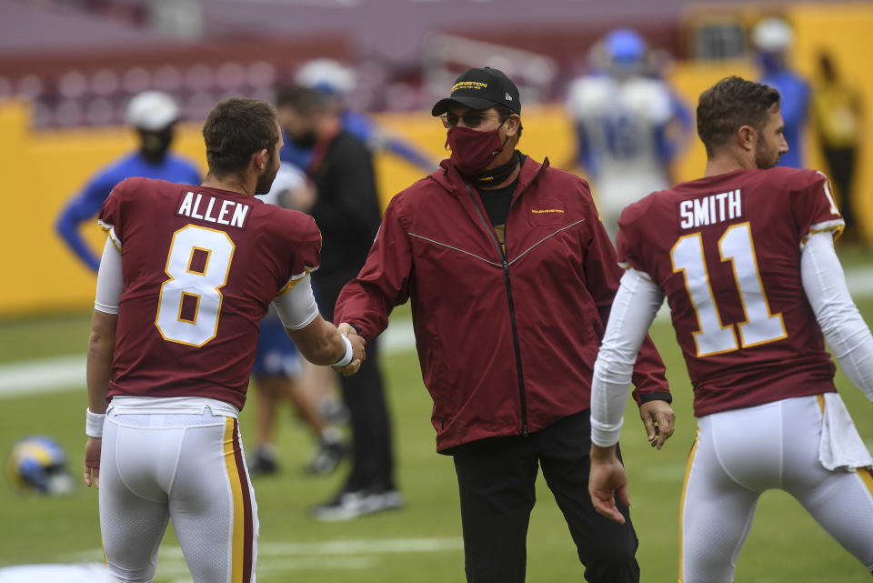  Washington Football Team head coach Ron Rivera shakes hands with Kyle Allen as Alex Smith warms up next to him.