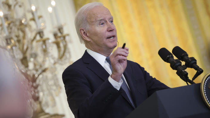 President Biden at the microphone, with a gilt candelabra behind him.