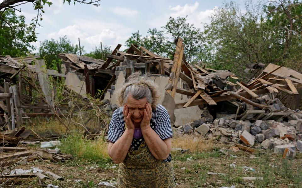 Valentina Chernaya, 90, reacts near her damaged house and destroyed outbuildings following recent shelling near Rozivka, Donetsk