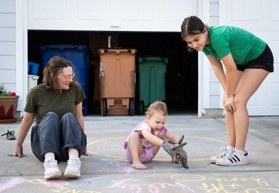 Lauren Vienne, left, sits in the family driveway with her two daughters, Leni Caplan, 2, and Cora Vienne, 13, in Park at 51 East, a community built on land previously owned by the school district.