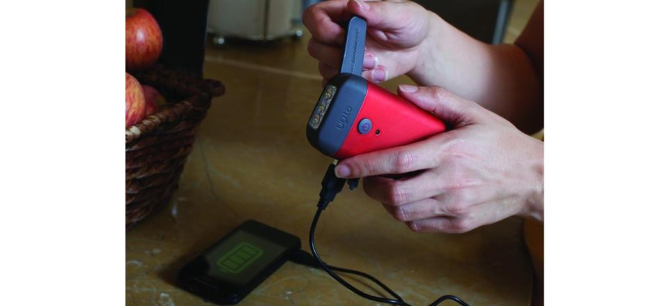 Person using Crank-Powered Flashlight and Smartphone Charger