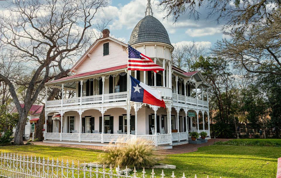 A grand white building in Gruene with the US and Texas flags flying in front