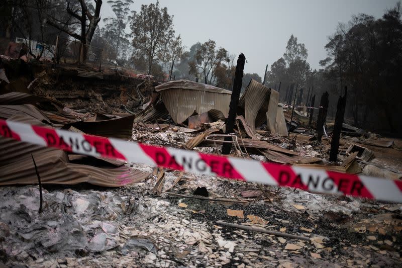 A cordon tape with the word "Danger" is seen in front of a burnt down shop in the village of Mogo