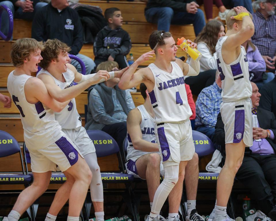 Jackson’s Ben Sullivan (left), Kevin James, JJ Vaughn, and Owen Woolbert celebrate on the bench during the fourth quarter against Hudson on Wednesday, Feb. 23, 2022.