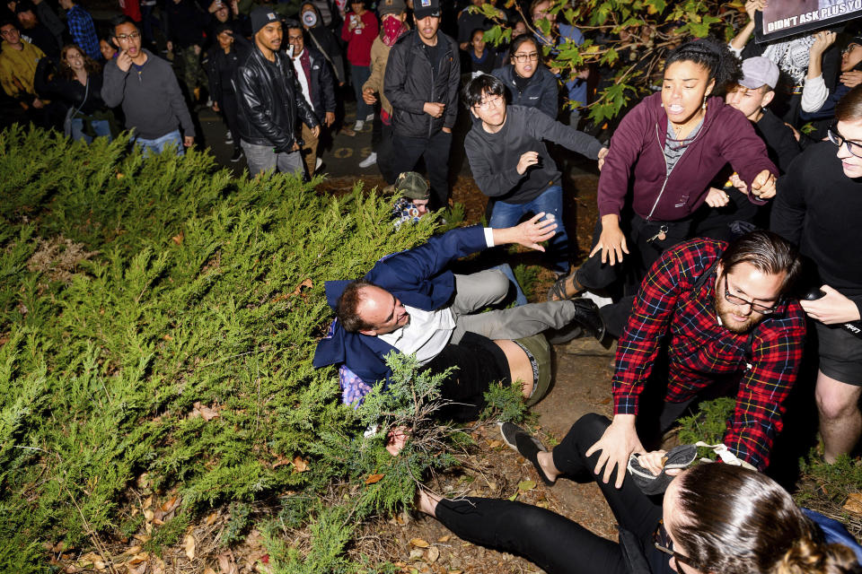 A man leaving a speech by conservative commentator Ann Coulter falls to the ground after being pushed by protesters at the University of California, Berkeley, Wednesday, Nov. 20, 2019, in Berkeley, Calif. Hundreds of demonstrators gathered as Coulter delivered a talk titled "Adios, America!" (AP Photo/Noah Berger)