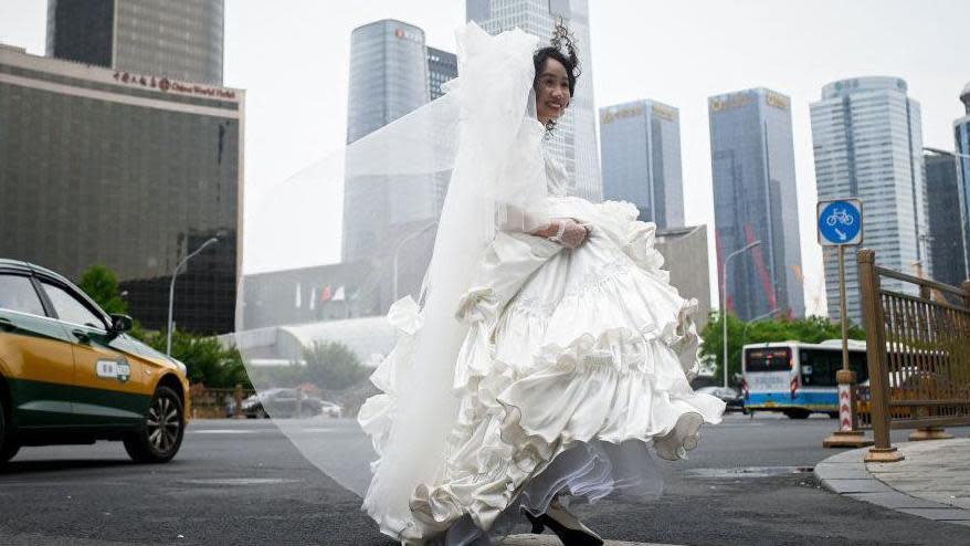Una joven con traje de novia corre por una calle