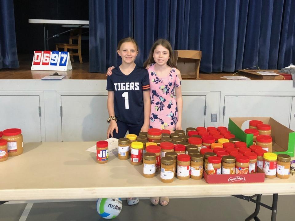 Trinity students Adalynn Telycenas (left) and Hannah Finley are shown with some of the collected jars of peanut butter.