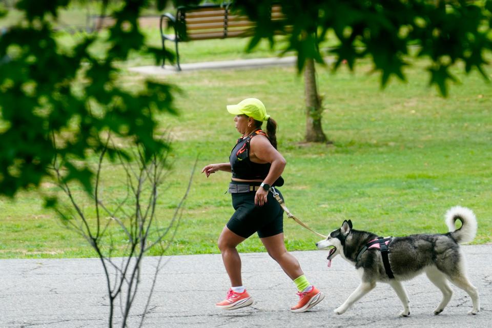 A woman and a dog run in Third Ward Park, Wednesday, July 24, 2024, in Passaic.