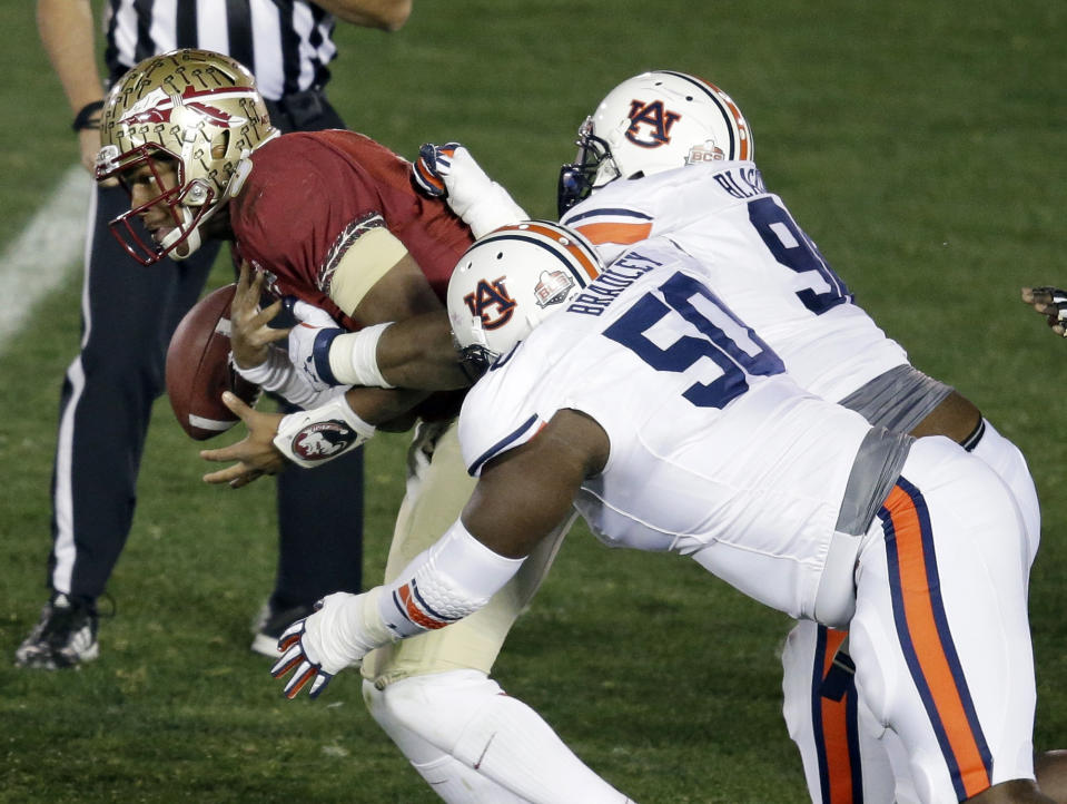 Florida State's Jameis Winston fumbles the ball as he is hit by Auburn's Ben Bradley (50)and Angelo Blackson during the first half of the NCAA BCS National Championship college football game Monday, Jan. 6, 2014, in Pasadena, Calif. (AP Photo/Gregory Bull)