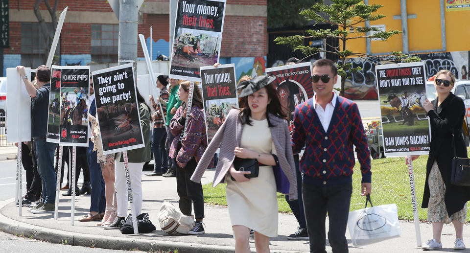 Race attendees walk past protestors to get to the Melbourne Cup