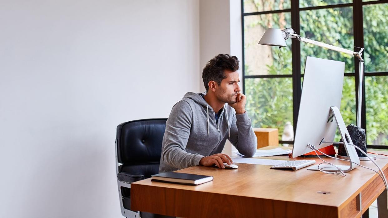 Shot of a young man working on a computer while sitting at a desk in his home office.