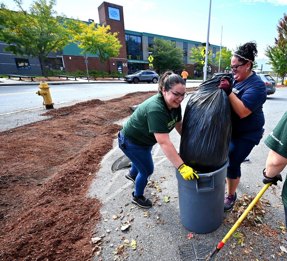 Webster Five bank employees Felicia Cierpich of Webster, left, and Tara Finn of West Boylston, work together Friday to pull up a trash bag full of leaves at the Boys & Girls Club of Worcester.