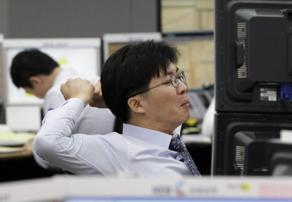A currency trader stretches during a morning session at the foreign exchange dealing room of the Korea Exchange Bank headquarters in Seoul, South Korea, Monday, June 18, 2012. Asian stock markets climbed Monday after elections in Greece eased fears of global financial turmoil, but analysts warned that the economic crisis shaking the 17 nations in the euro common currency was far from over. (AP Photo/Ahn Young-joon)