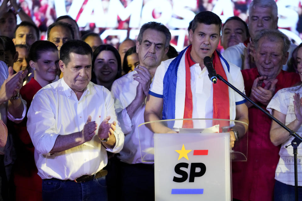 Santiago Peña, candidato presidencial del Partido Colorado gobernante, a la derecha, en una intervención junto al expresidente paraguayo Horacio Cartes tras el cierre de urnas en las elecciones generales, en Asunción, Paraguay, el domingo 30 de abril de 2023. Con un 43,15% de los votos, al 90 % de escrutinio, la tendencia irreversible coloca a Peña como nuevo presidente de Paraguay y confirma cinco años más de mandato para el oficialismo. (AP Foto/Jorge Sáenz)