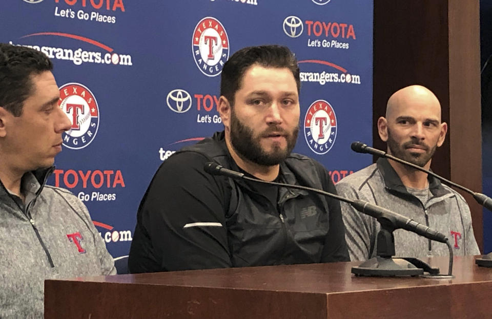Newly signed Texas Rangers pitcher, Lance Lynn, center, responds to reporters questions as team general manager Jon Daniels, left, and manager Chris Woodward, right, look on in Arlington, Texas, Tuesday, Dec. 18, 2018. (AP Photo/Stephen Hawkins)