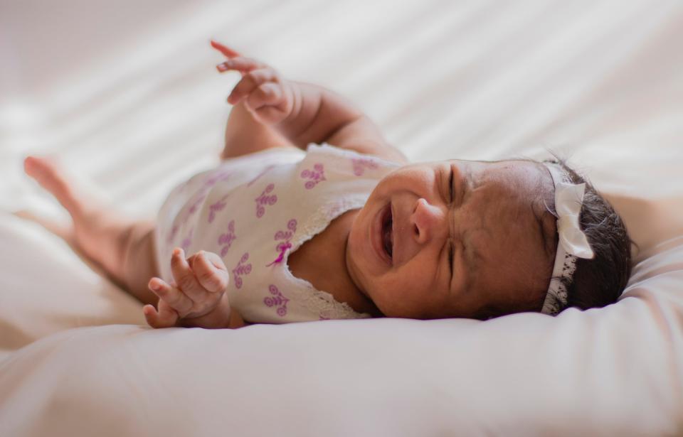 A baby crying on a bed