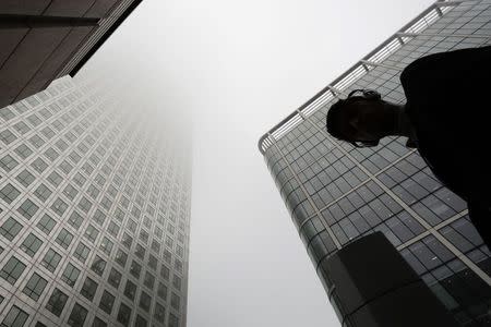 A man walks past a building in the morning mist at London's financial district of Canary Wharf September 16, 2014. REUTERS/Kevin Coombs