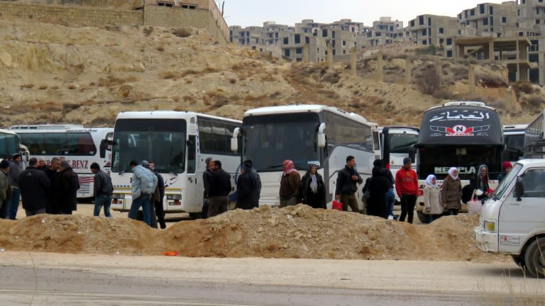 Syrians gather around buses as they prepare to leave the town of Ain al-Fijah, in the Wadi Barada region, on January 14, 2017