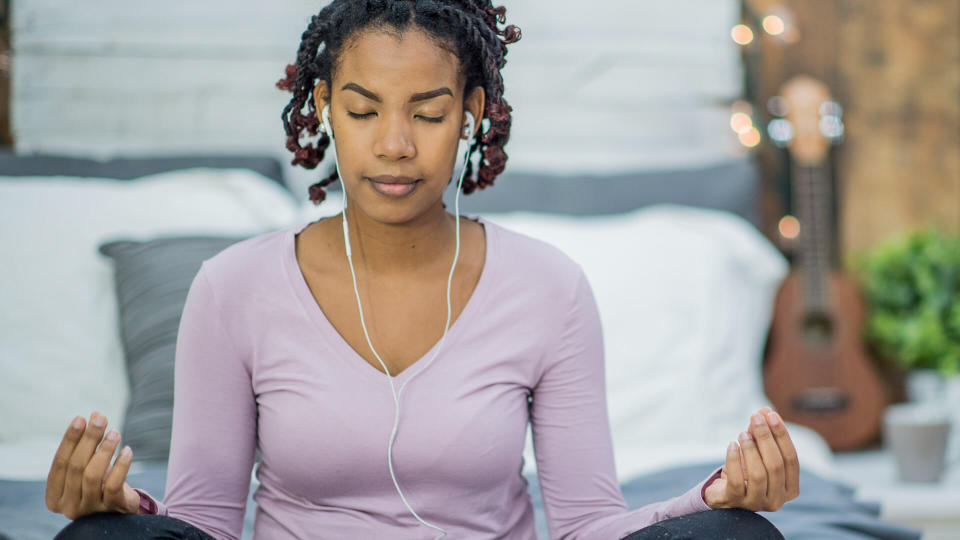 A woman of African descent is indoors in her bedroom.