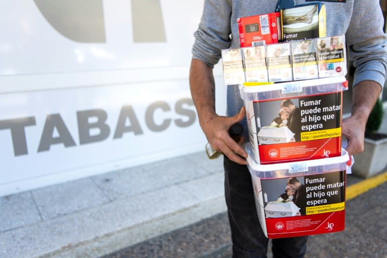 Un hommes porte des paquets de tabac achetéd dans une boutique de Les, en Espagne, le 19 avril 2024 (Matthieu RONDEL)