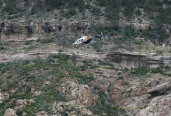 <p>A helicopter flies above the rugged terrain along the banks of the East Verde River during a search and rescue operation for victims of a flash flood on Sunday, July 16, 2017, in Payson, Ariz. (AP Photo/Ralph Freso) </p>