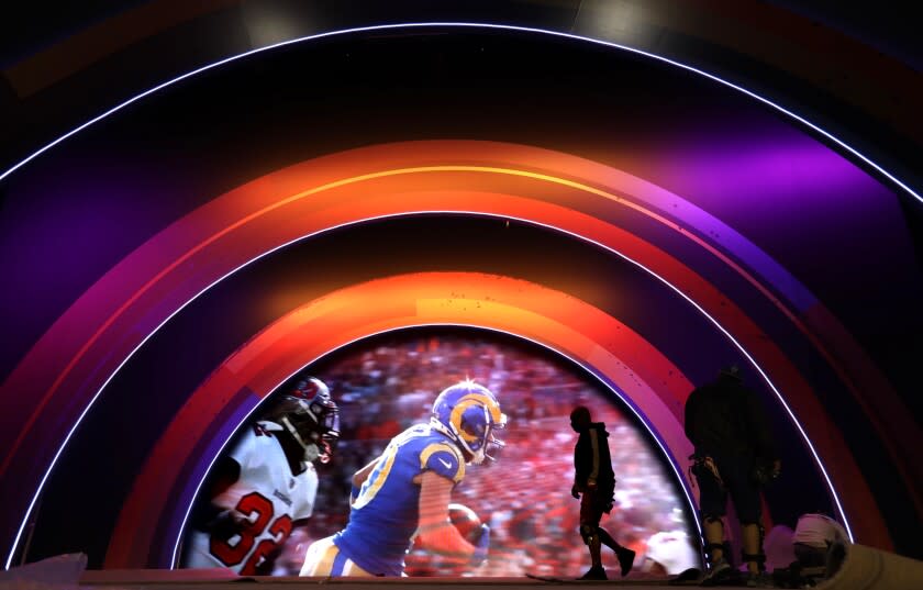 LOS ANGELES, CA - FEBRUARY 4, 2022 - - A worker preps the main stage while a video of a past Rams game is screened at the Super Bowl LVI Experience, an interactive football theme park at the Los Angeles Convention Center in Downtown Los Angeles on February 4, 2022. Media were allowed to observe and interact with the attractions in the final stages of installation ahead of the public grand opening on Saturday, February 5. In case it wasn't already a draw for Super Bowl fans across the region, L.A. City officials are incentivizing the Super Bowl LVI Experience, by offering free COVID-19 tests and incentives to earn free entry and fast passes on all days. It will be open on February 5, 6 along with February 10 through the 12th. The Super Bowl LVI Experience is presented by Lowe's, the NFL Shop and Visa. (Genaro Molina / Los Angeles Times)