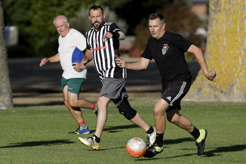 In this Wednesday, Feb. 26, 2020, photo, Al Noor mosque shooting survivor Temel Atacocugu, center, gestures during a social game of soccer in Christchurch, New Zealand. When the gunman walked into the mosque, Atacocugu was kneeling for Friday prayers. He looked up into the man's face, thinking he was a police officer because of his paramilitary outfit. Time slowed. Temel saw a puff of smoke come from the raised gun, felt a bullet smash into his teeth, and thought: "Oh, my God, I'm dying." (AP Photo/Mark Baker)