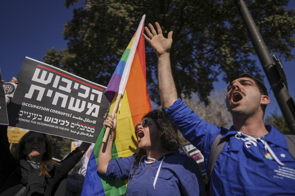 Protesters waving a rainbow flag, often symbolizing the LGBTQ+ community, and a sign that reads in Hebrew "the occupation corrupts" protest Benjamin Netanyahu's new government in front of Israel's Parliament in Jerusalem, Thursday, Dec. 29, 2022. Netanyahu returned to office Thursday at the helm of the most religious and ultranationalist government in Israel's history, vowing to implement policies that could cause domestic and regional turmoil and alienate the country's closest allies. (AP Photo/Oded Balilty)