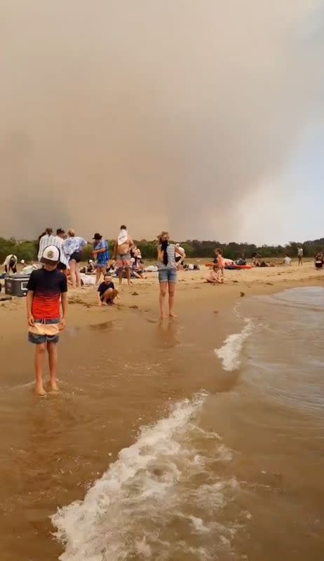 People at the beach evacuate from the bushfires at Batemans Bay