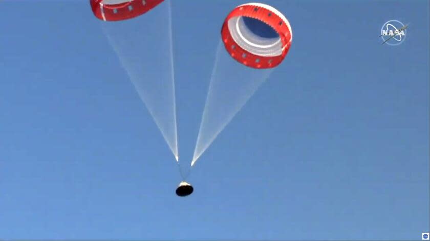 In this image made from a video provided by NASA parachutes guide the Starliner capsule to the ground after a test of Boeing's crew capsule's launch abort system in White Sands Missile Range in N.M., on Monday, Nov. 4, 2019. The capsule carried no astronauts Monday morning, just a test dummy. (NASA via AP)