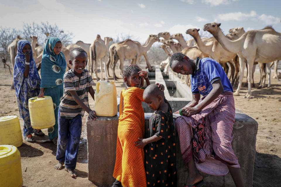 Herder children who look after their family's camels cool off and fill plastic containers with water from a water point in the desert near Dertu, Wajir County, Kenya Sunday, Oct. 24, 2021. As world leaders address a global climate summit in Britain, drought has descended yet again in northern Kenya, the latest in a series of climate shocks rippling through the Horn of Africa. (AP Photo/Brian Inganga)