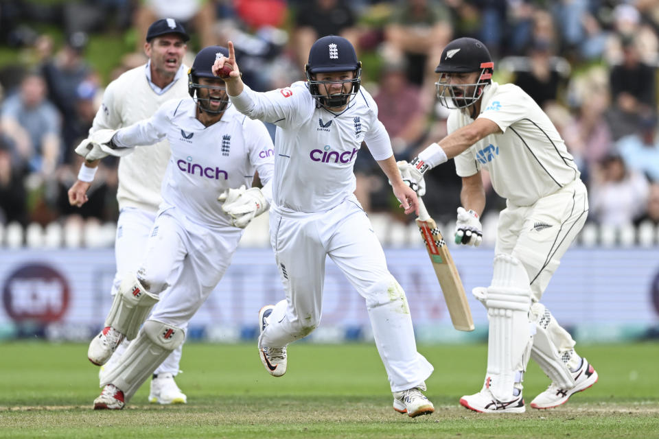 Ollie Pope, left, of England celebrates after taking a close in catch to dismiss Daryl Mitchell, right, of New Zealand on the second day of the second cricket test between England and New Zealand at the Basin Reserve in Wellington, New Zealand, Saturday, Feb. 25, 2023. (Andrew Cornaga/Photosport via AP)